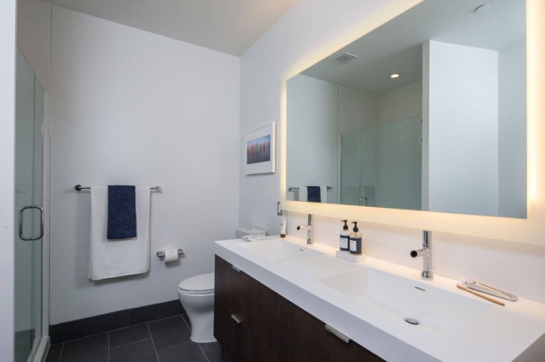 modern bathroom with toilet, large vanity and mirror