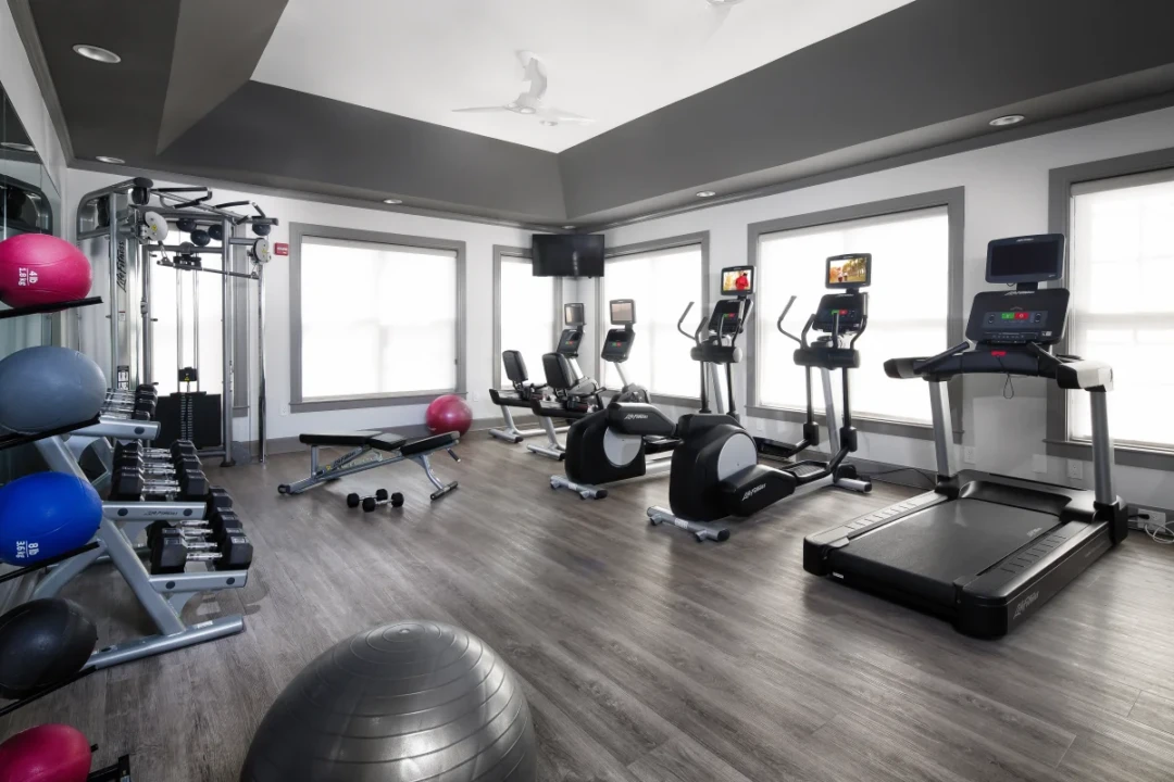 Fitness center with cardio machines, weights, exercise balls, and a workout bench.