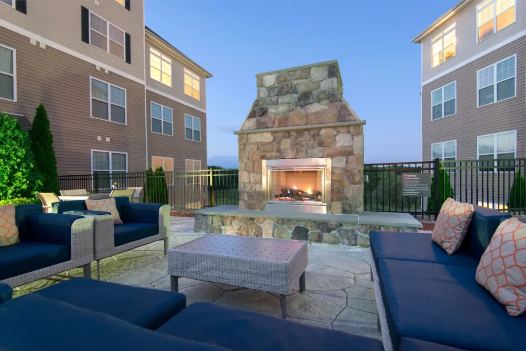 utdoor lounge with blue cushioned seating arranged around a large stone fireplace.