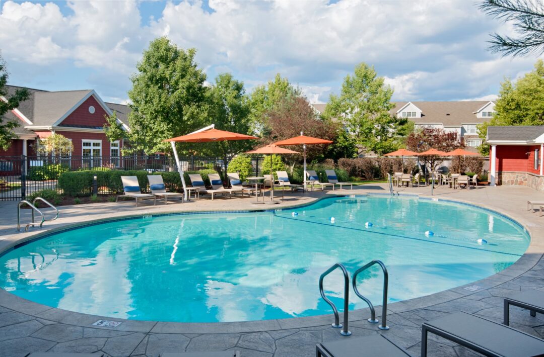 Lounge chairs surrounding a sparkling apartment complex swimming pool