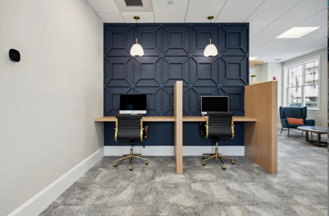common area work stations featuring 2 desks and chairs with computers and privacy panel in between