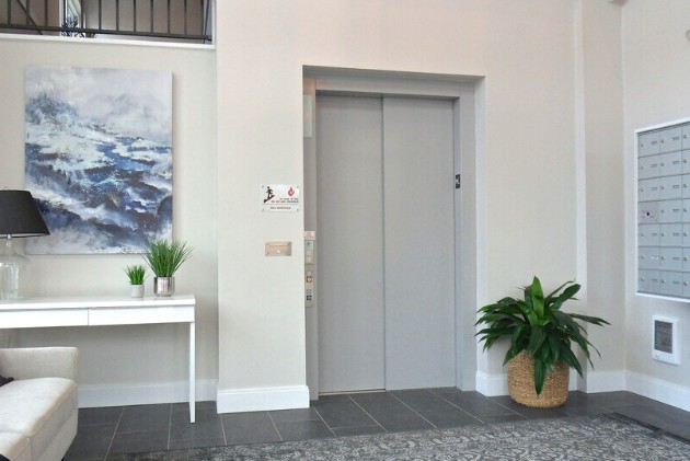 Two closed silver elevator doors set into a modern apartment lobby