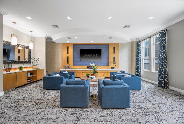 Modern apartment resident lounge featuring large couches, tv and table with chair in the background