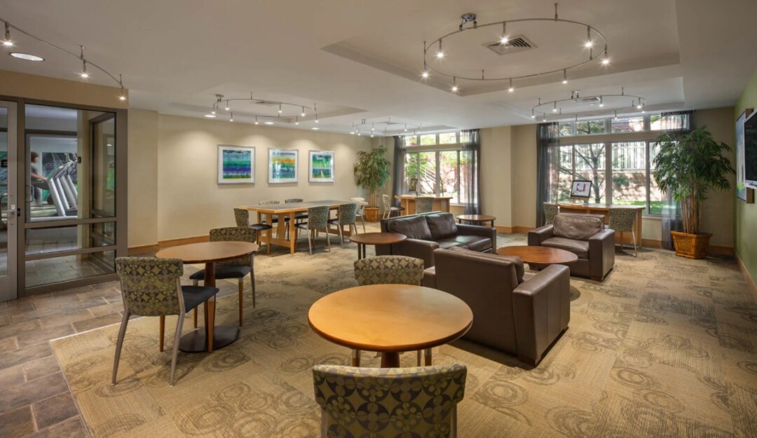 open and airy resident lounge featuring tables, chairs and large windows