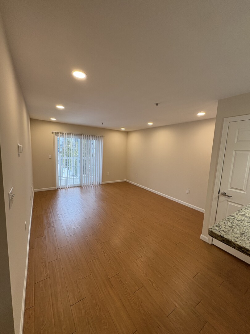 open concept living room with wood floors, natural light and white walls