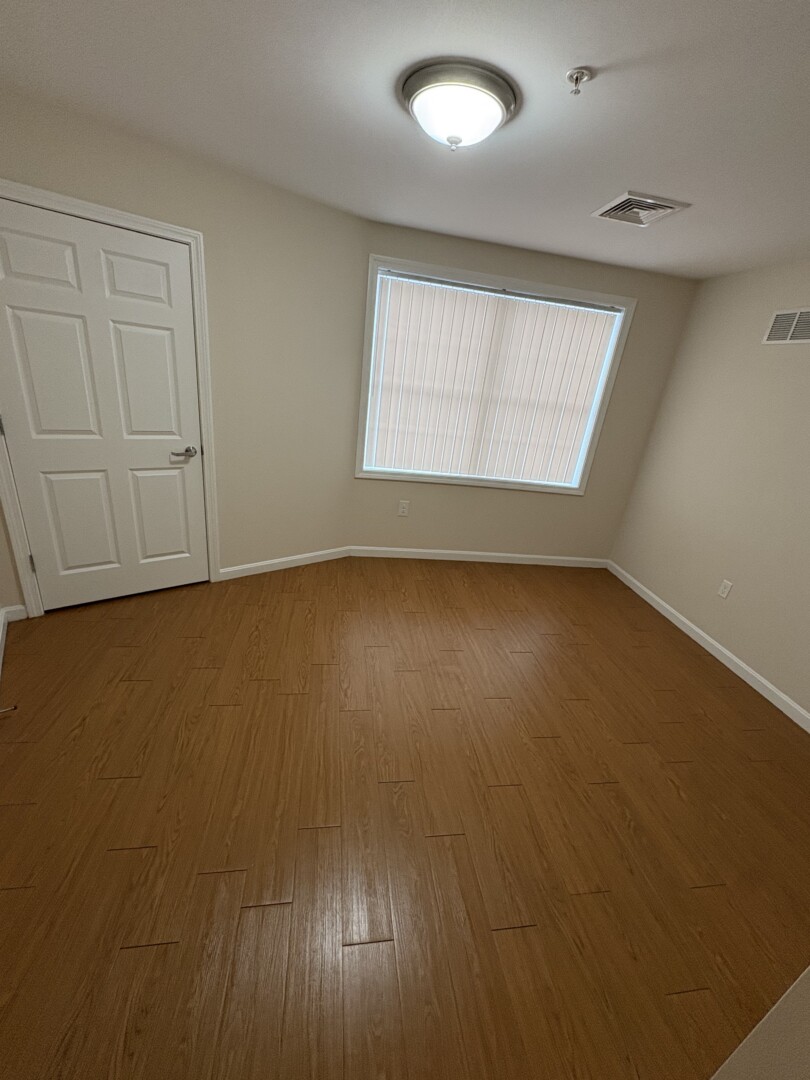 small white bedroom with natural light and wood floors
