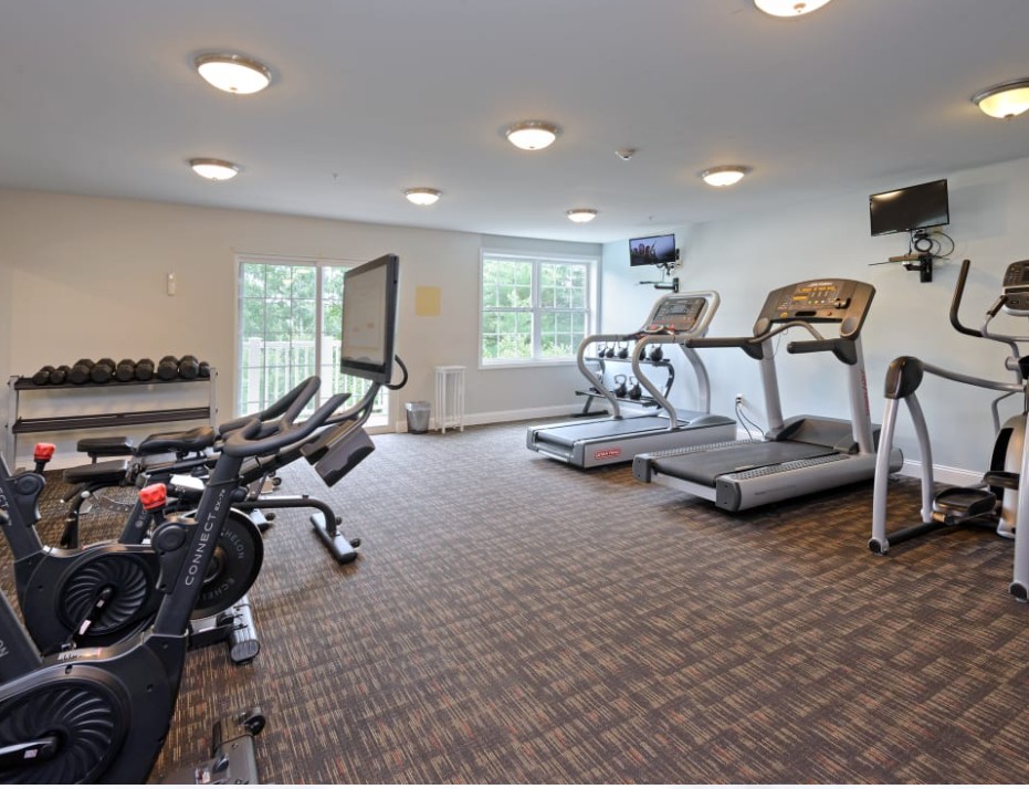 modern fitness center with ceiling lights and a variety of workout equipment