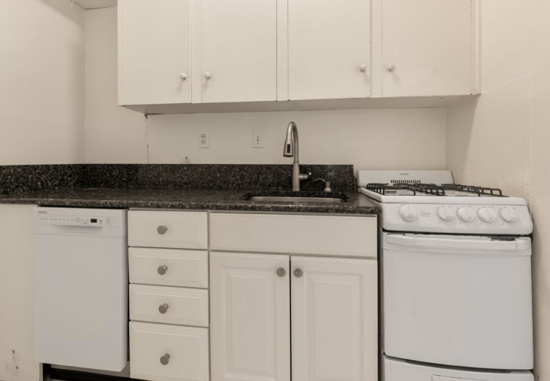 Kitchen featuring white cabinets, dark countertop, stainless steel sink, and gas range.