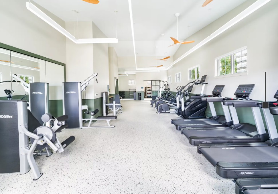 Spacious fitness center equipped with treadmills, exercise machines, and ceiling fans.